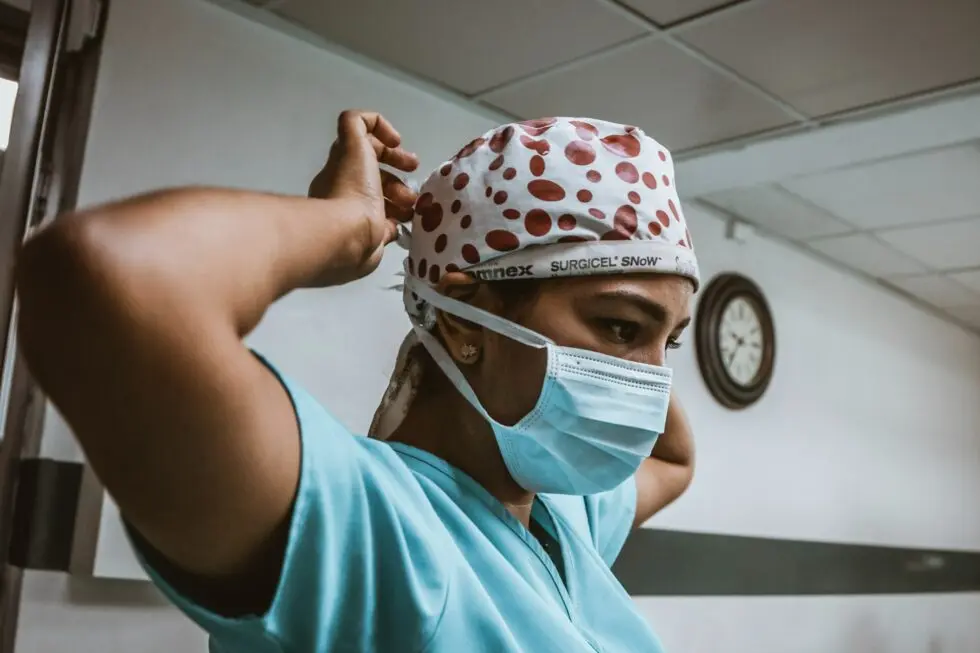 A nurse puts on their hair covering
