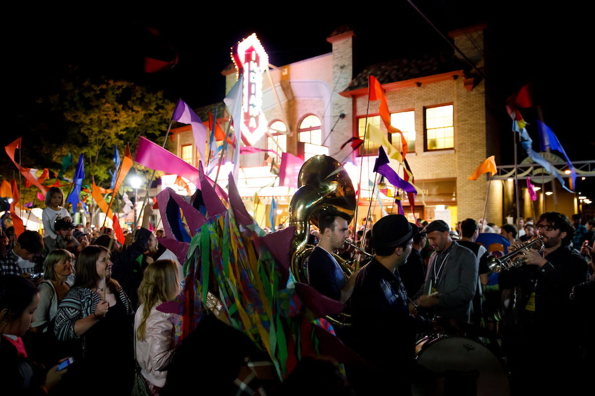 crowds with banners and flags fill the street at the lotus festival in downtown bloomington