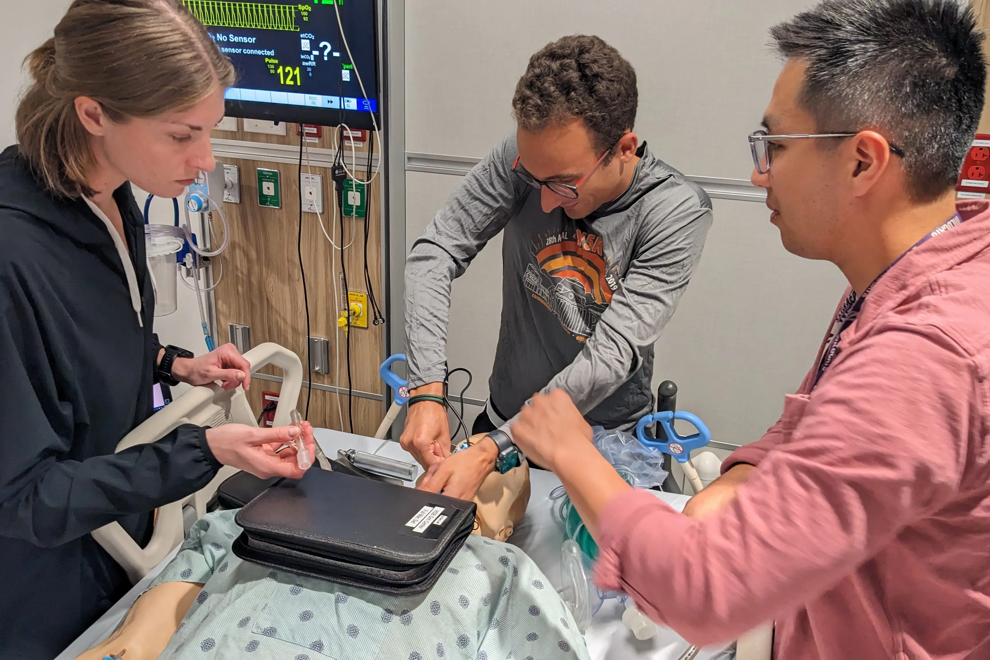 students work on a mannequin in a hospital bed in the sim center