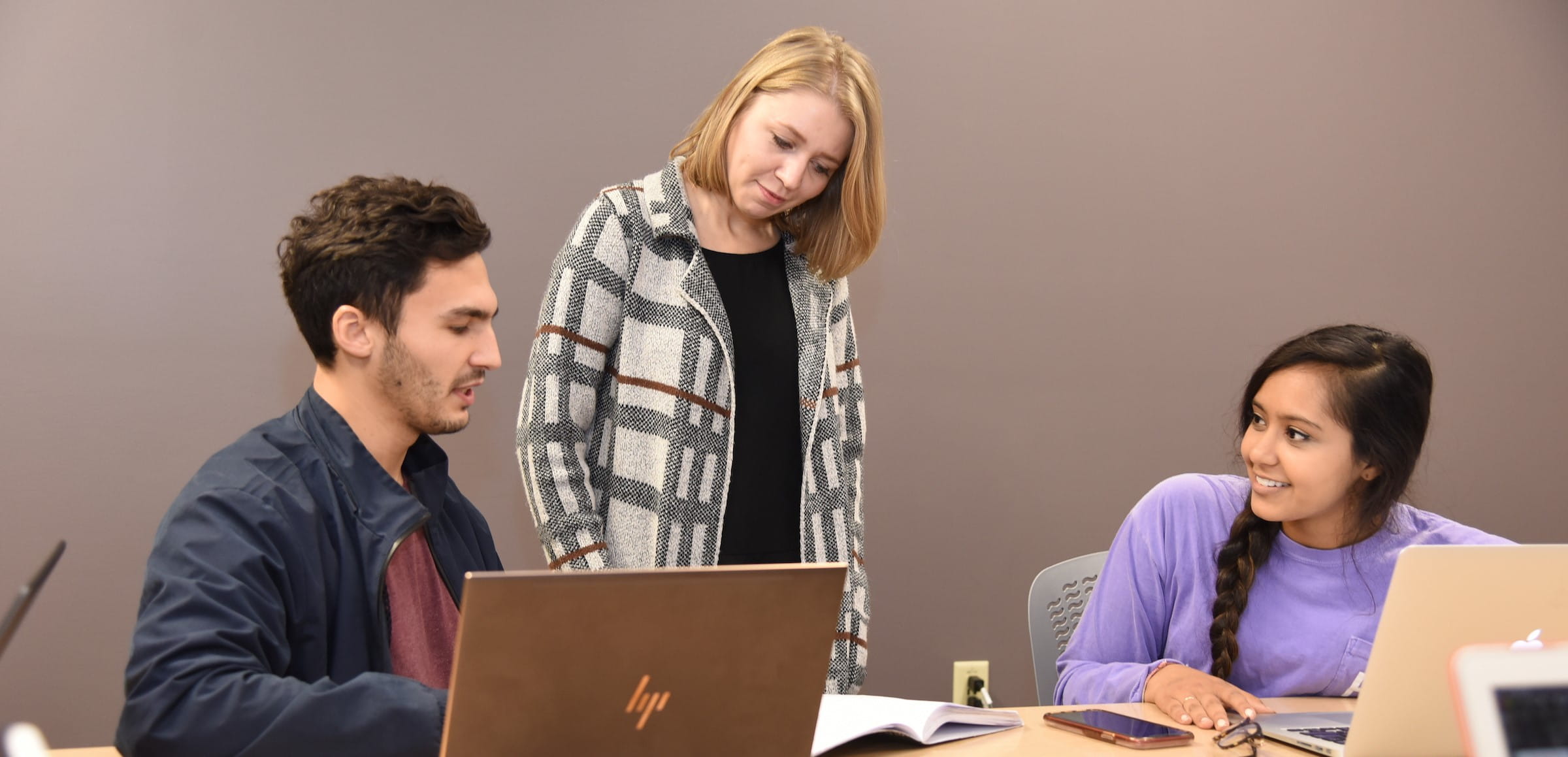 a faculty member and students work together in a classroom in evansville