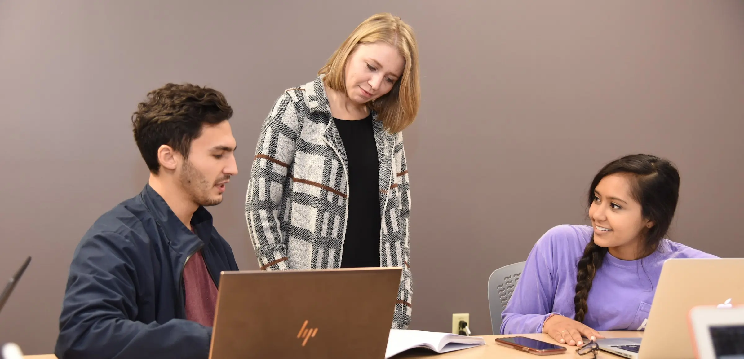 a faculty member and students work together in a classroom in evansville