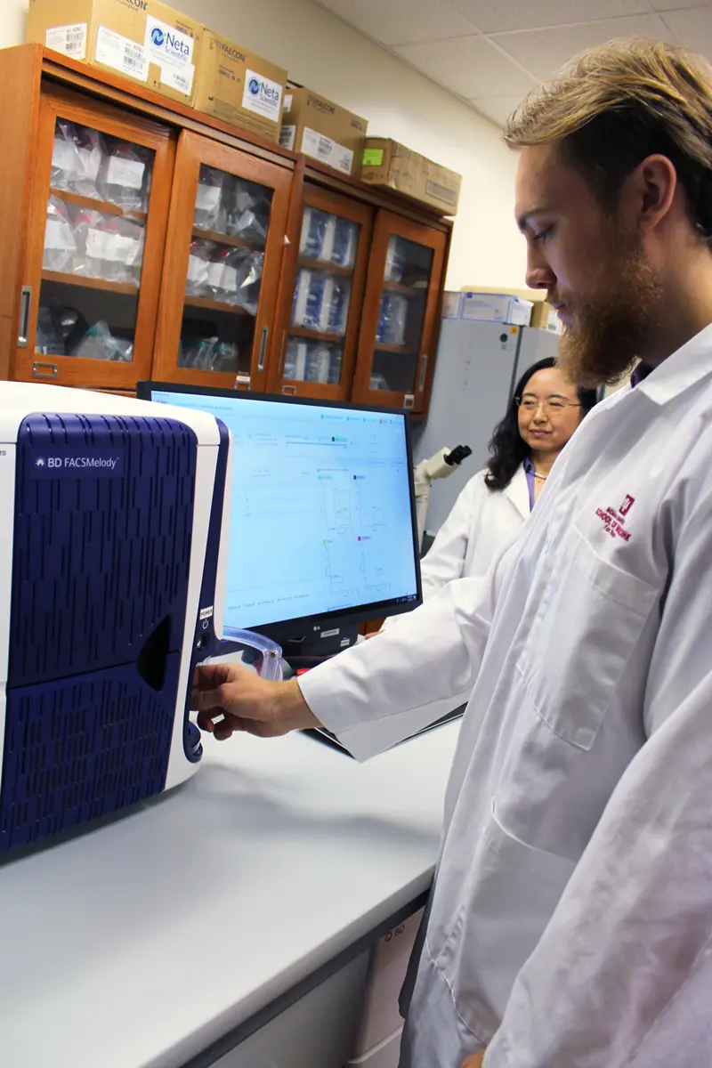 a student inserts a sample into a scientific instrument in the lab