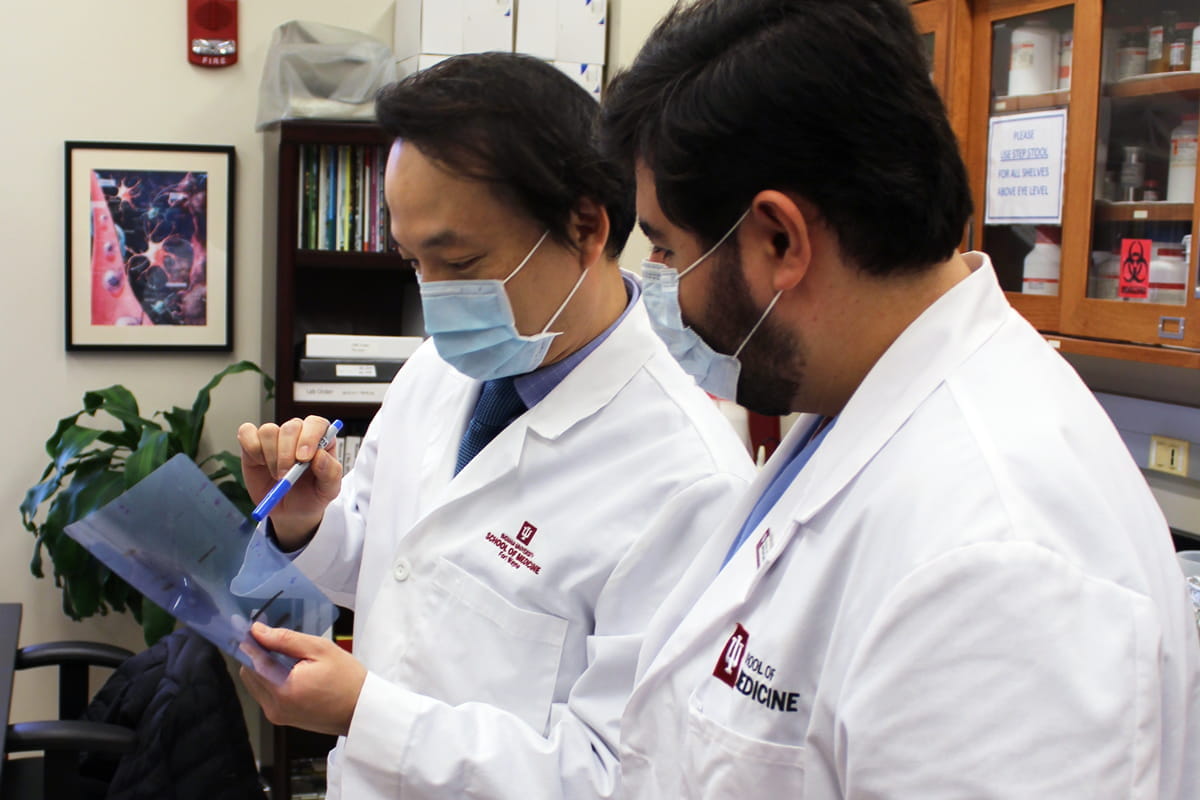 a researcher and a student review data in the lab