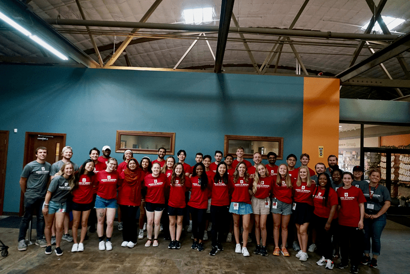 a huge group photo of students standing with their arms around each other after working at the food bank in gary