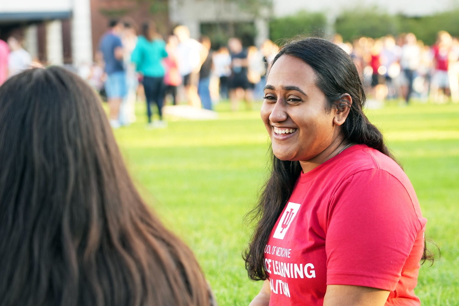 two students sit on the grass on a sunny day outside on the IU Indianapolis campus