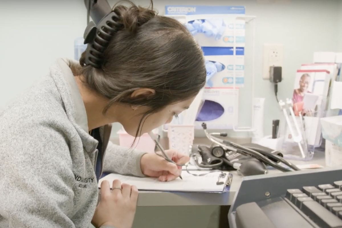 a student is working diligently writing on a pad in a clinical setting