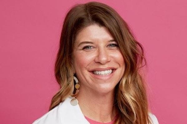 Headshot of Carla Fisher against a pink background.
