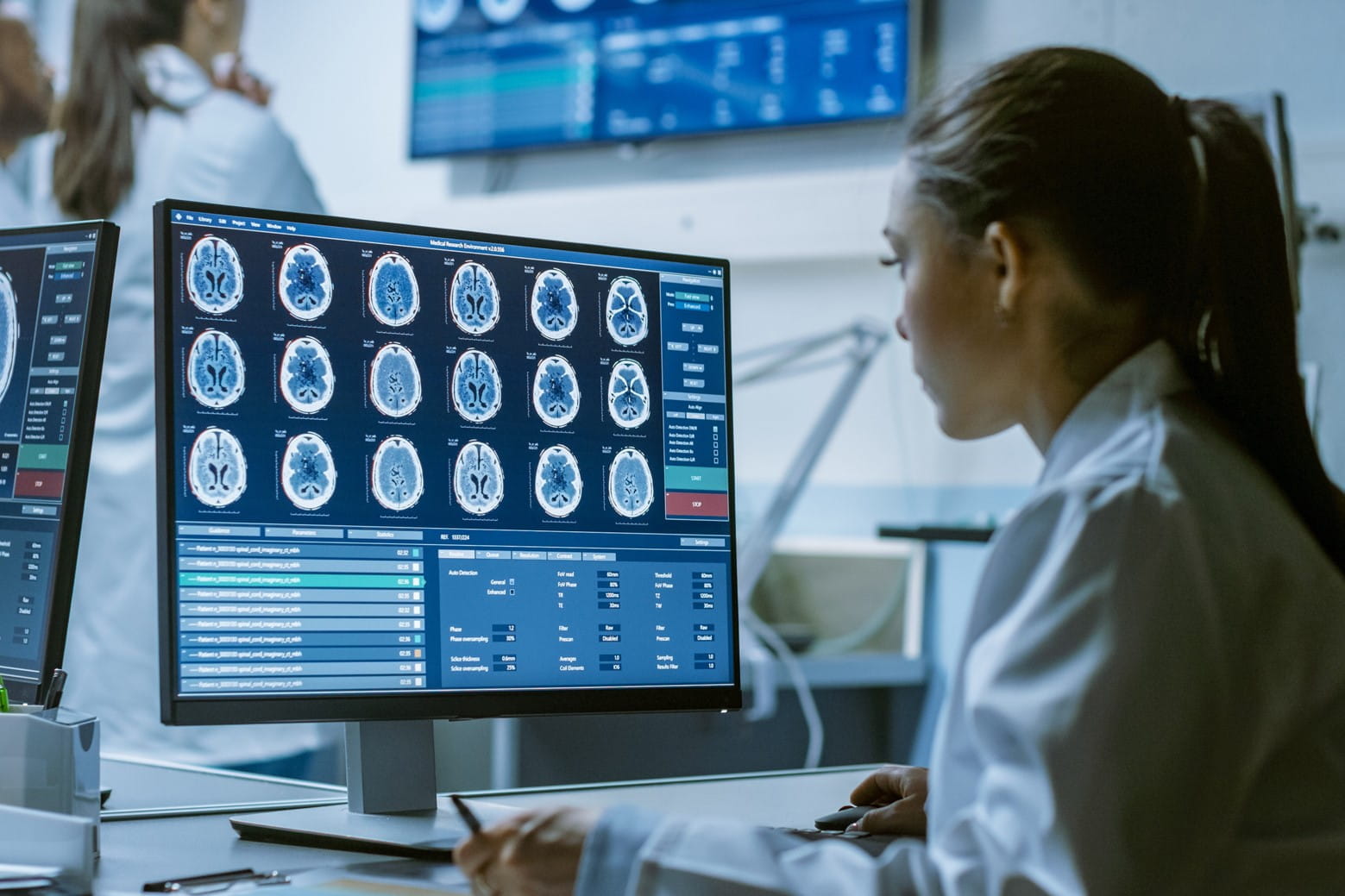 a woman in a lab coat takes notes as she examines brain imaging