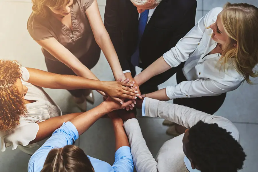 a team of people put their hands together in a group huddle