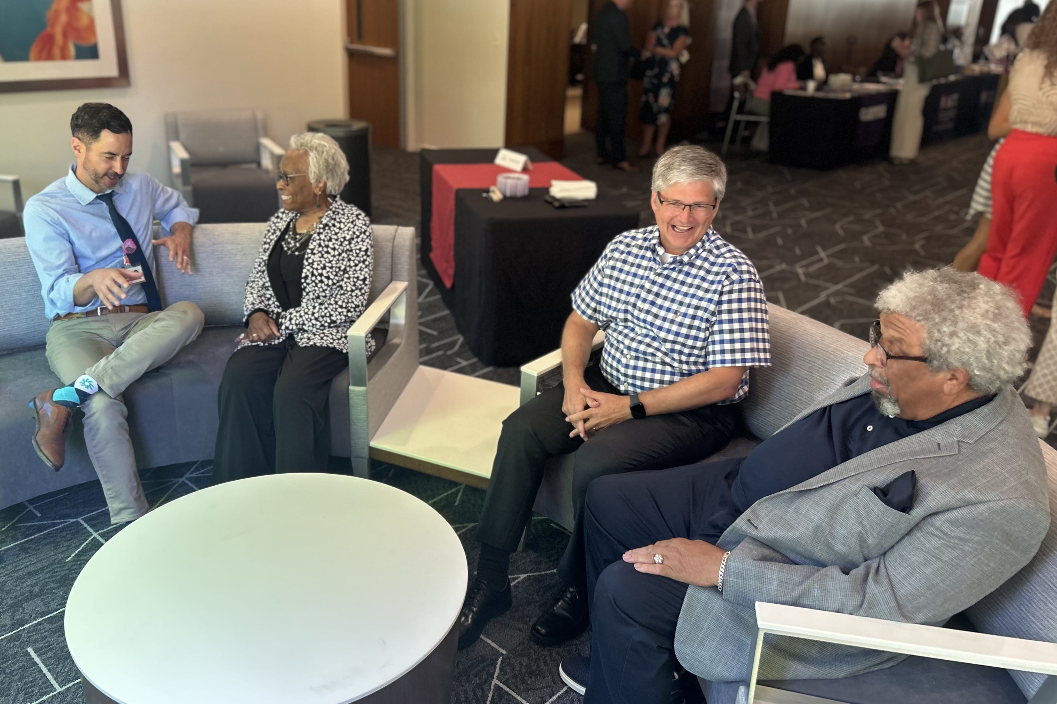 Community advisory board members and faculty members sit talking together at an event reception.