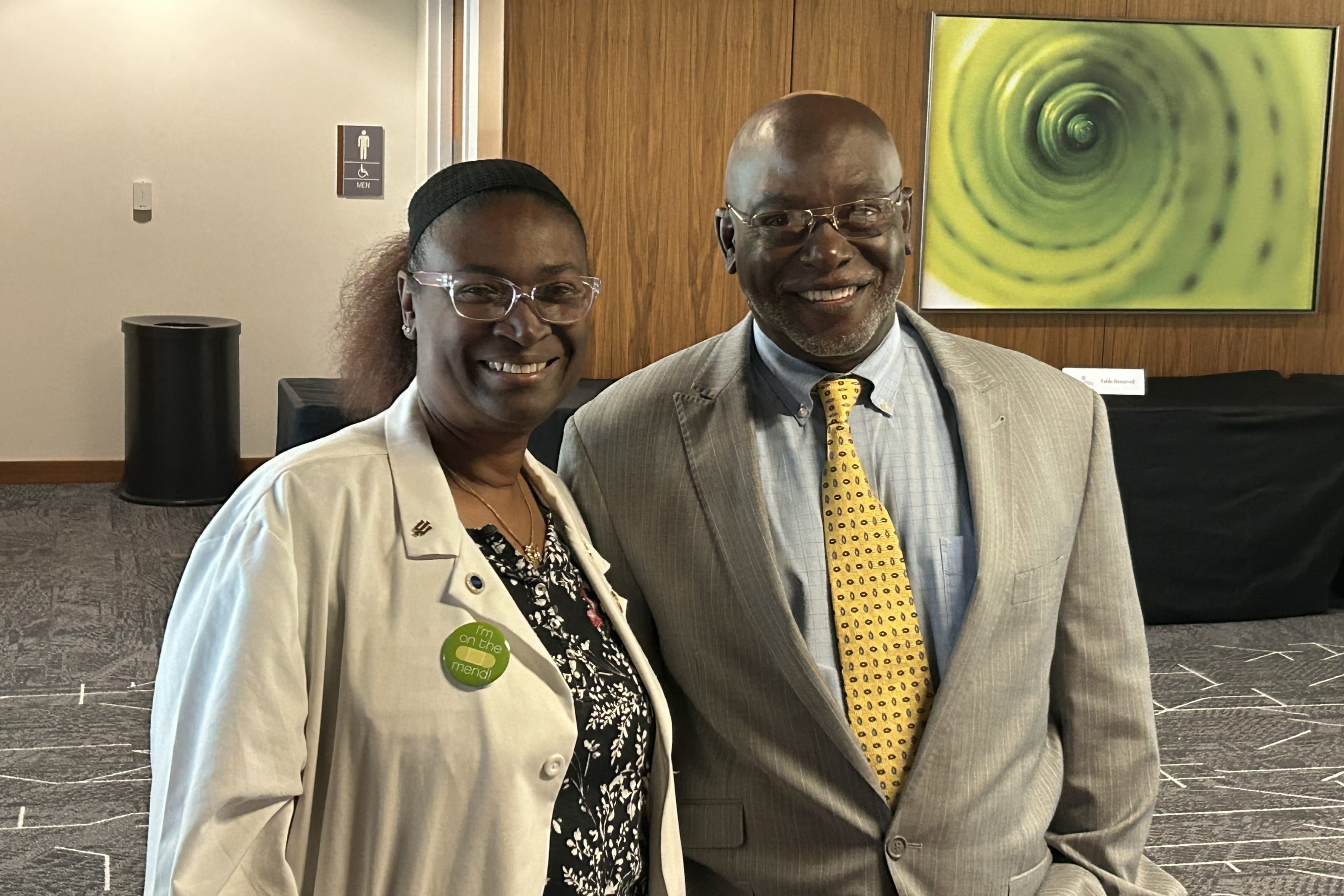 Two African-American community advisory board members stand together in an event space.