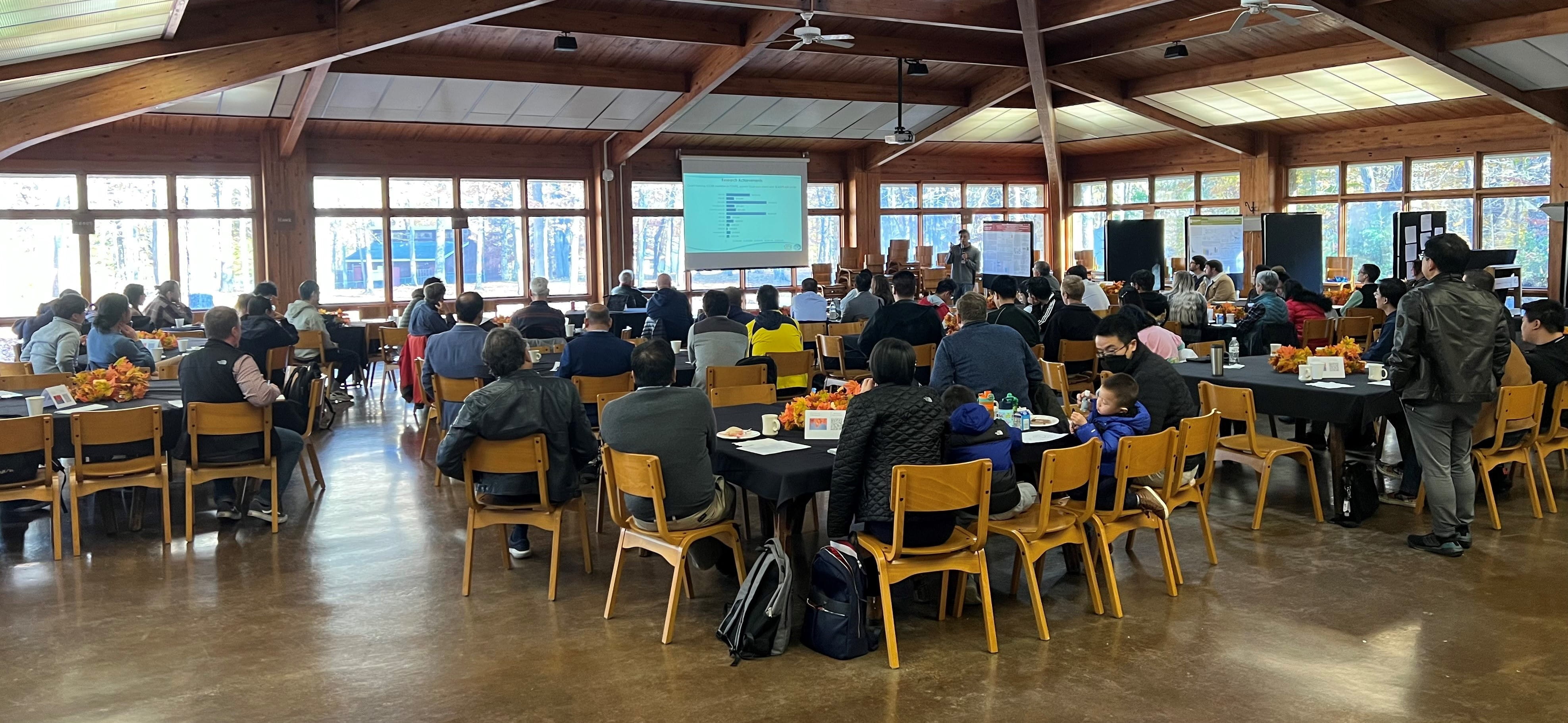 a large group of people gather for the CCBB retreat in a large bright and airy room