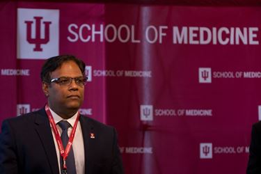 Dr. Dharmakumar stands in front of an IU School of Medicine podium background