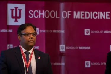 Dr. Dharmakumar stands in front of an IU School of Medicine podium background