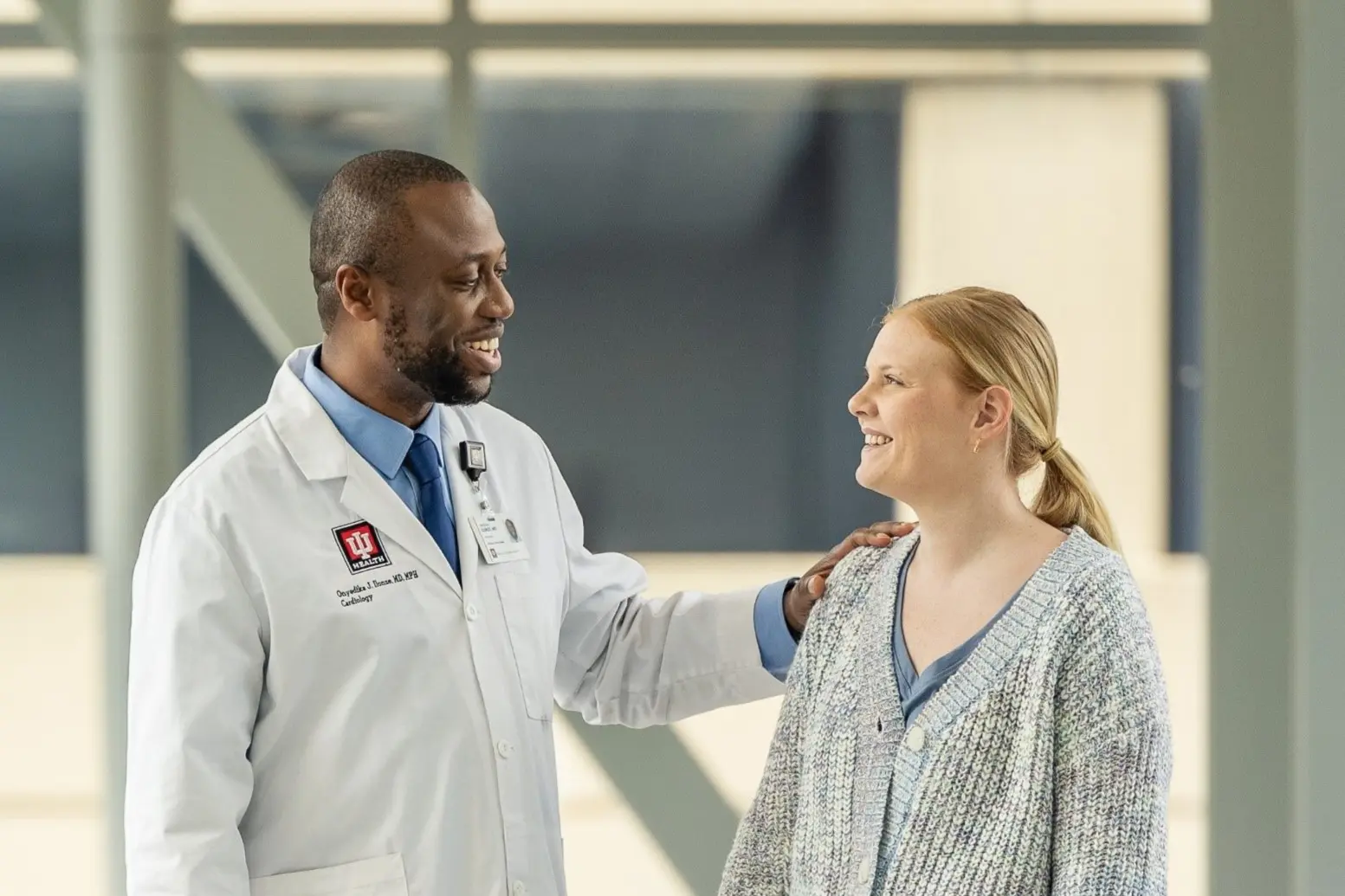Doctor in white coat consoles patient outside clinic.