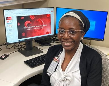 Halimat Olaniyan, MD, sitting at her desk with one of her sickle cell presentations on the computer monitor.