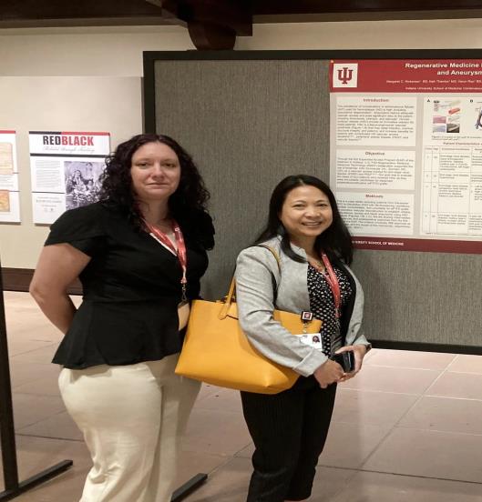 Two women from the Krannert Cardiovascular Research Center stand near their poster presentation.
