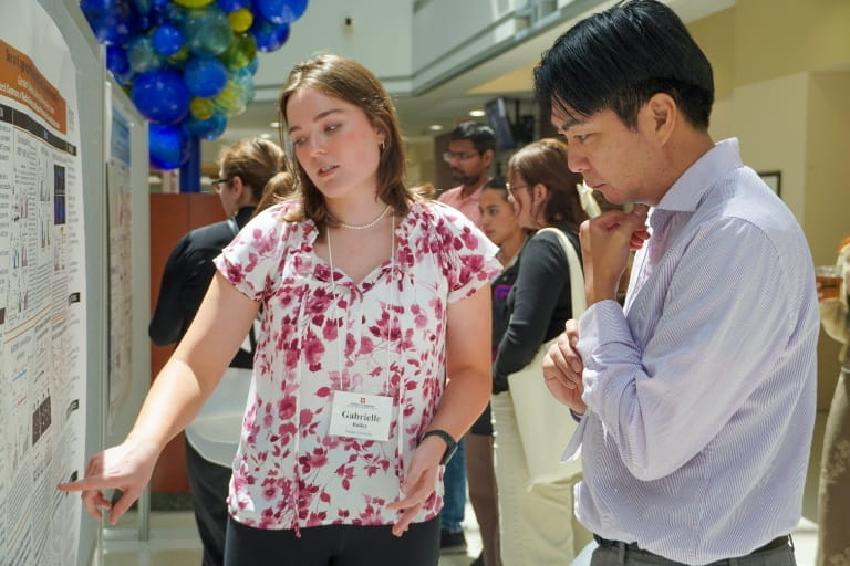 Two symposium attendees looking at a research poster at the 2024 CDMD Symposium.