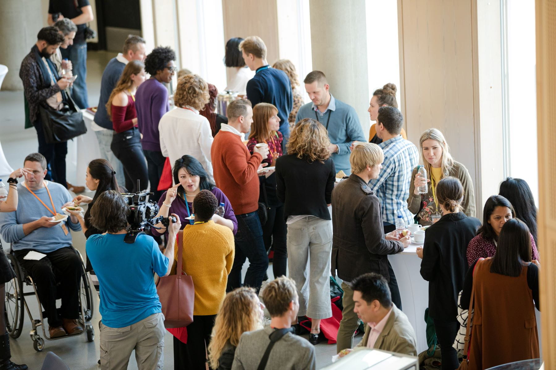 A diverse group of conference attendees mingle and enjoy refreshments.