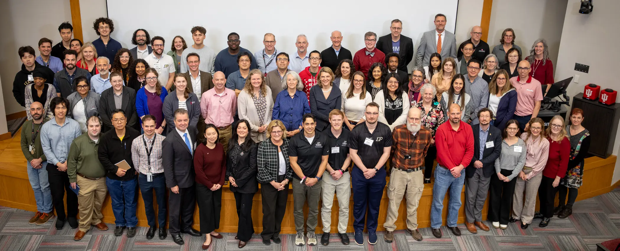 a very large group of musculoskeletal researchers lined up for a group photo on a conference room stage
