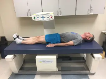 a man lays on a table with a bone density scan machine moving over his body