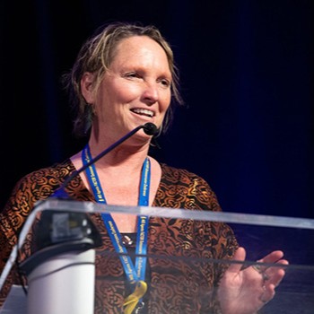 Janet Panoch speaks on stage at a podium