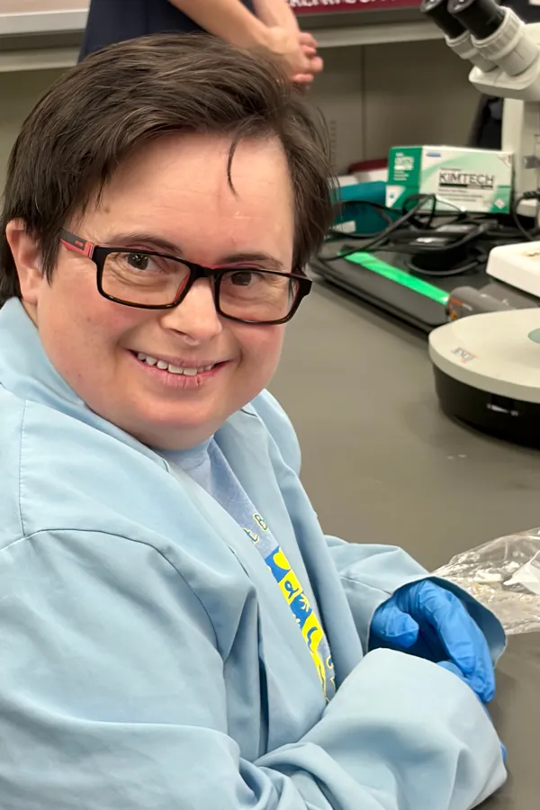 a person with down syndrome wearing a lab coat and gloves