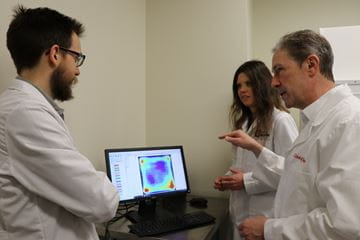 three scientist reviewing data on a computer monitor
