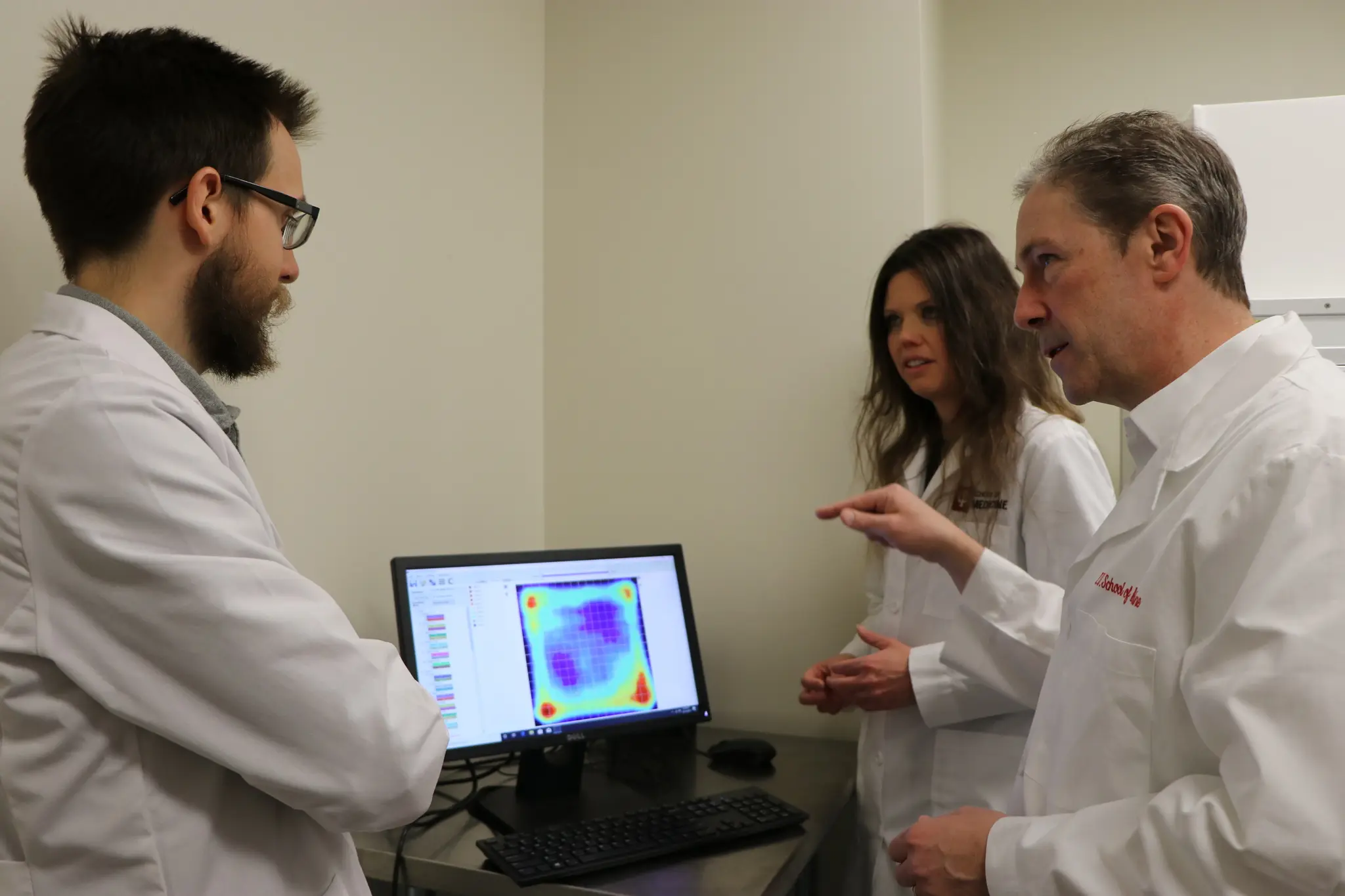 three scientist reviewing data on a computer monitor