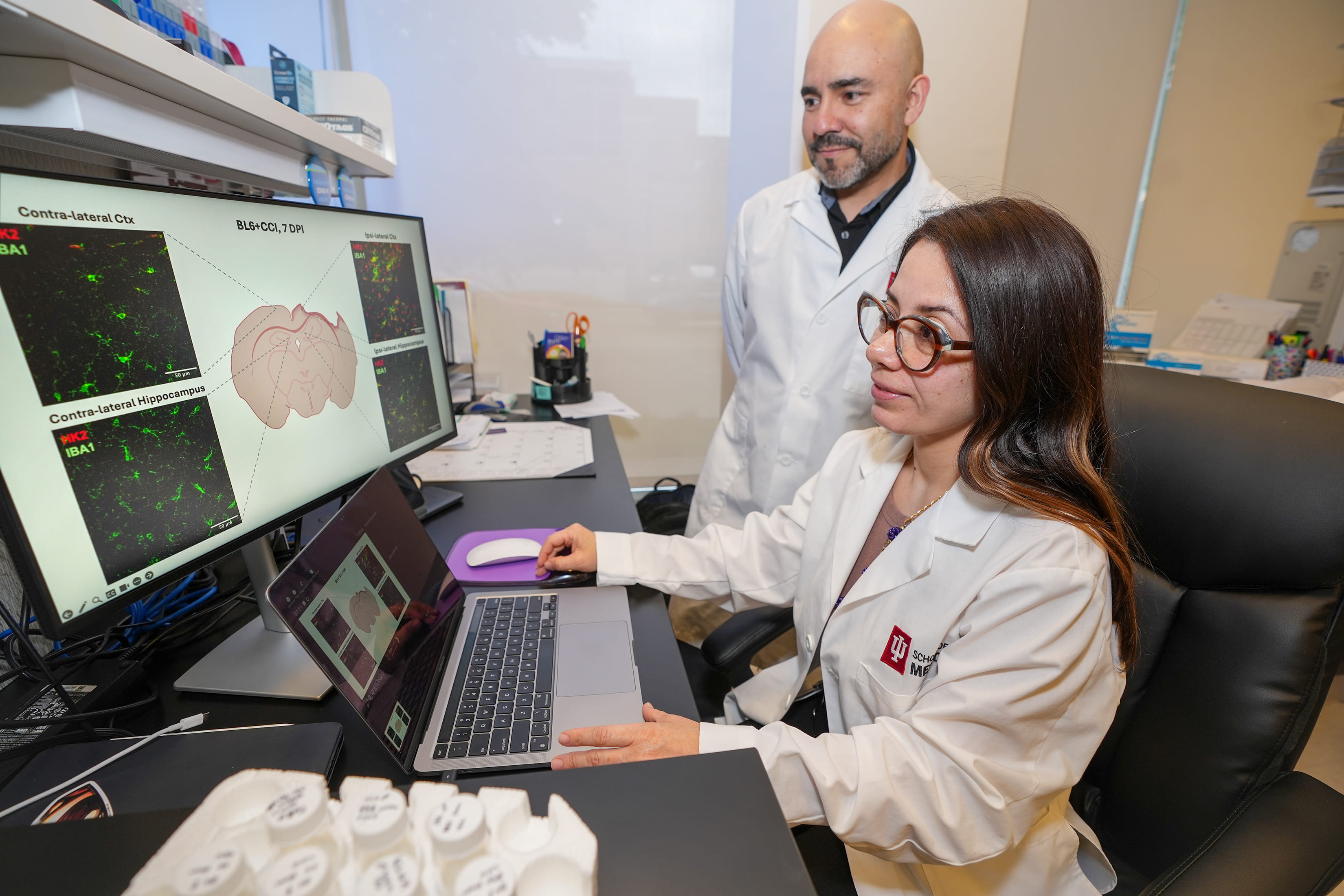 Two researchers in a lab look at a computer monitor