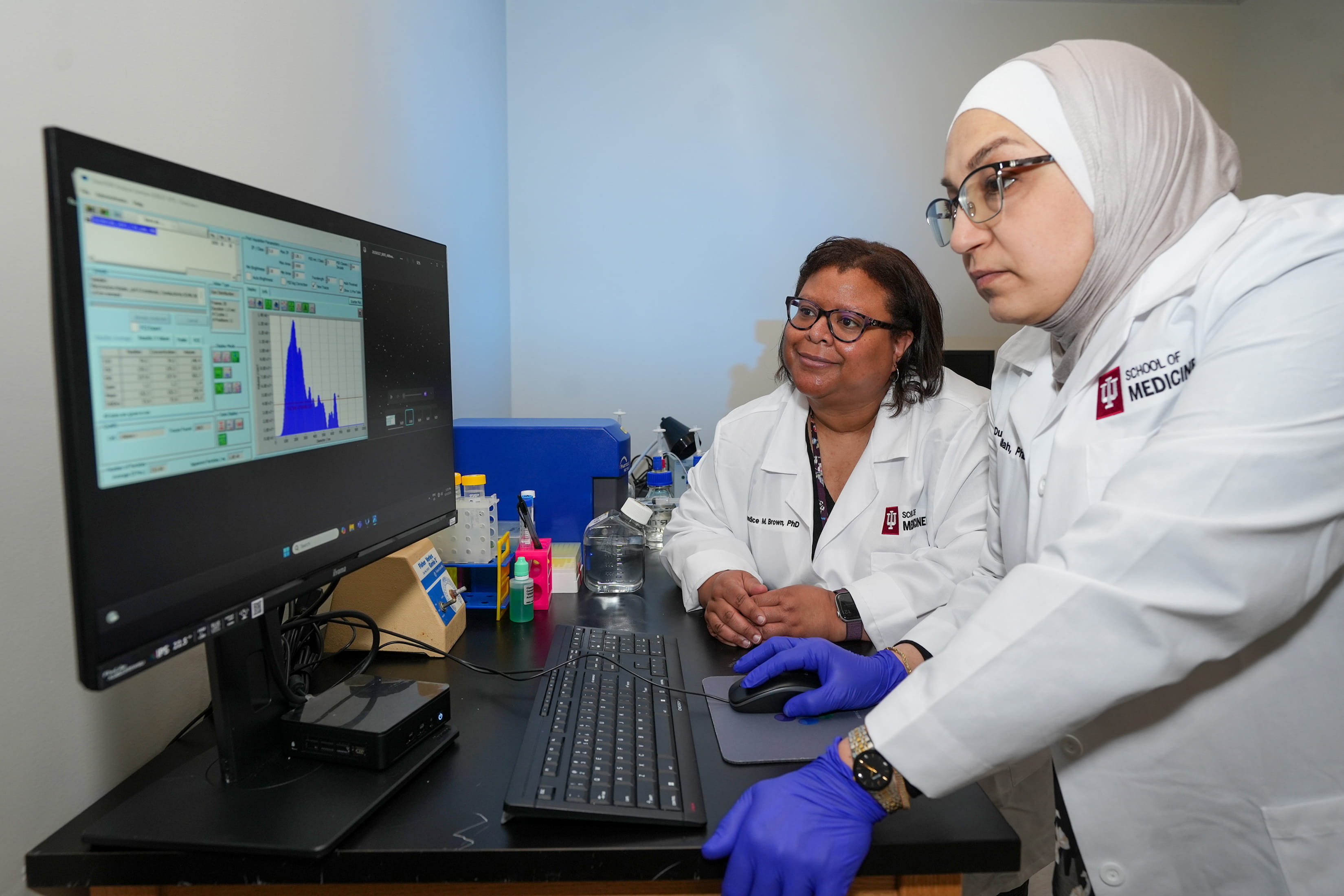 two researchers work at a computer in a lab