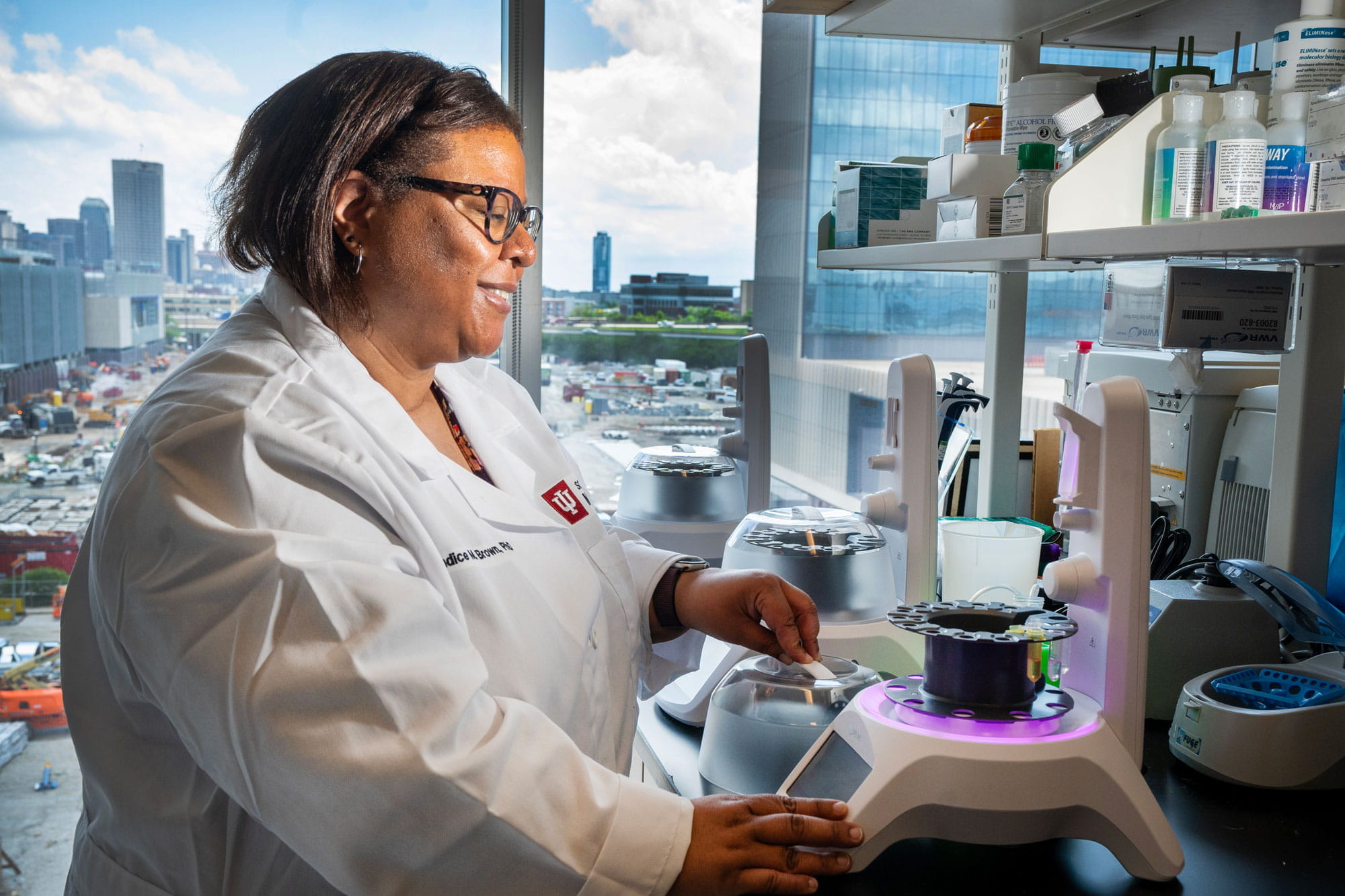 Candice Brown works in her research lab with the Indianapolis skyline in the background