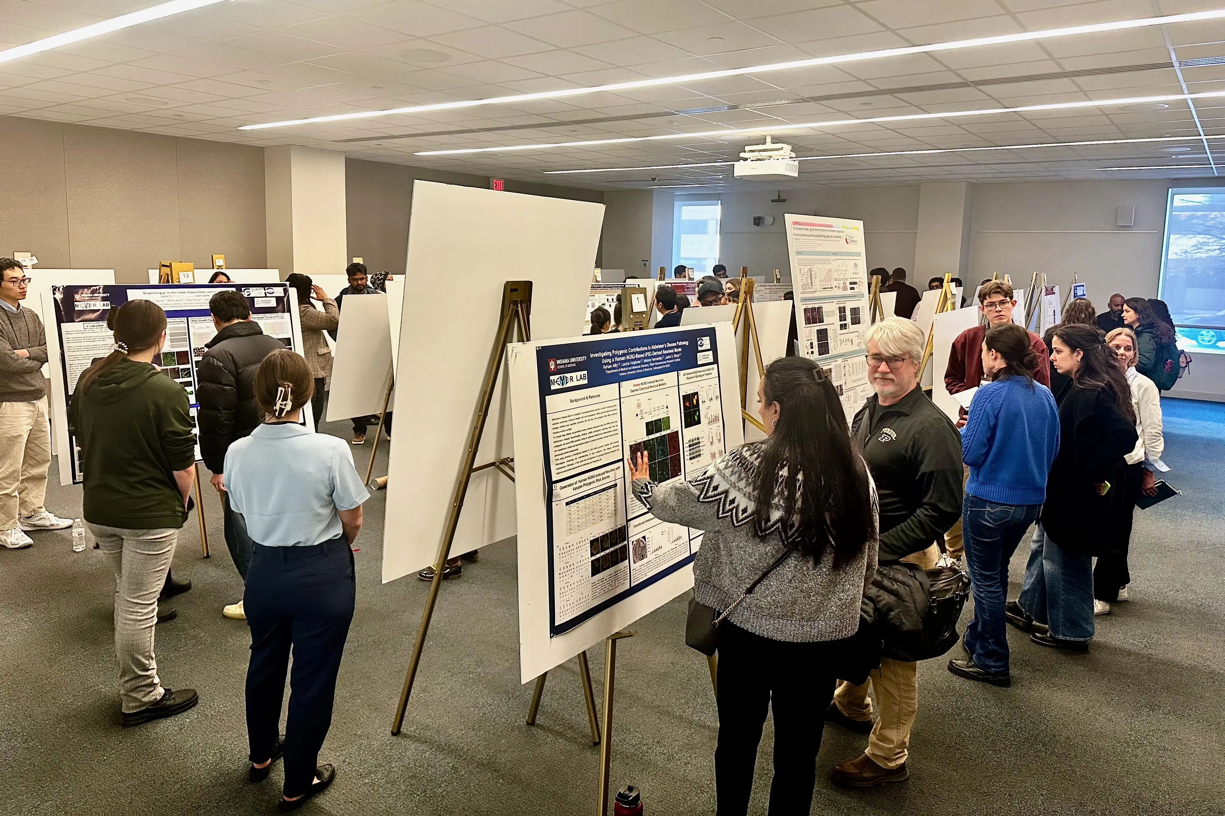 researchers present posters in a room at a symposium