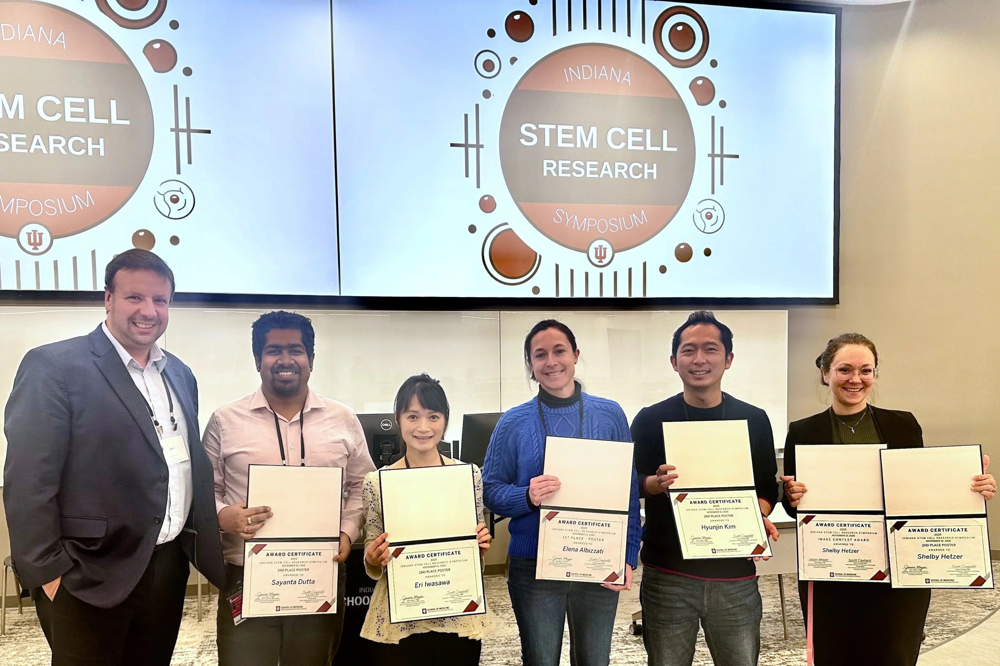 a group of researchers present their awards at a symposium