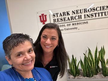 two women stand in front of a sign for Stark Neurosciences Research Institute
