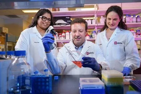 Three researchers work at a lab bench