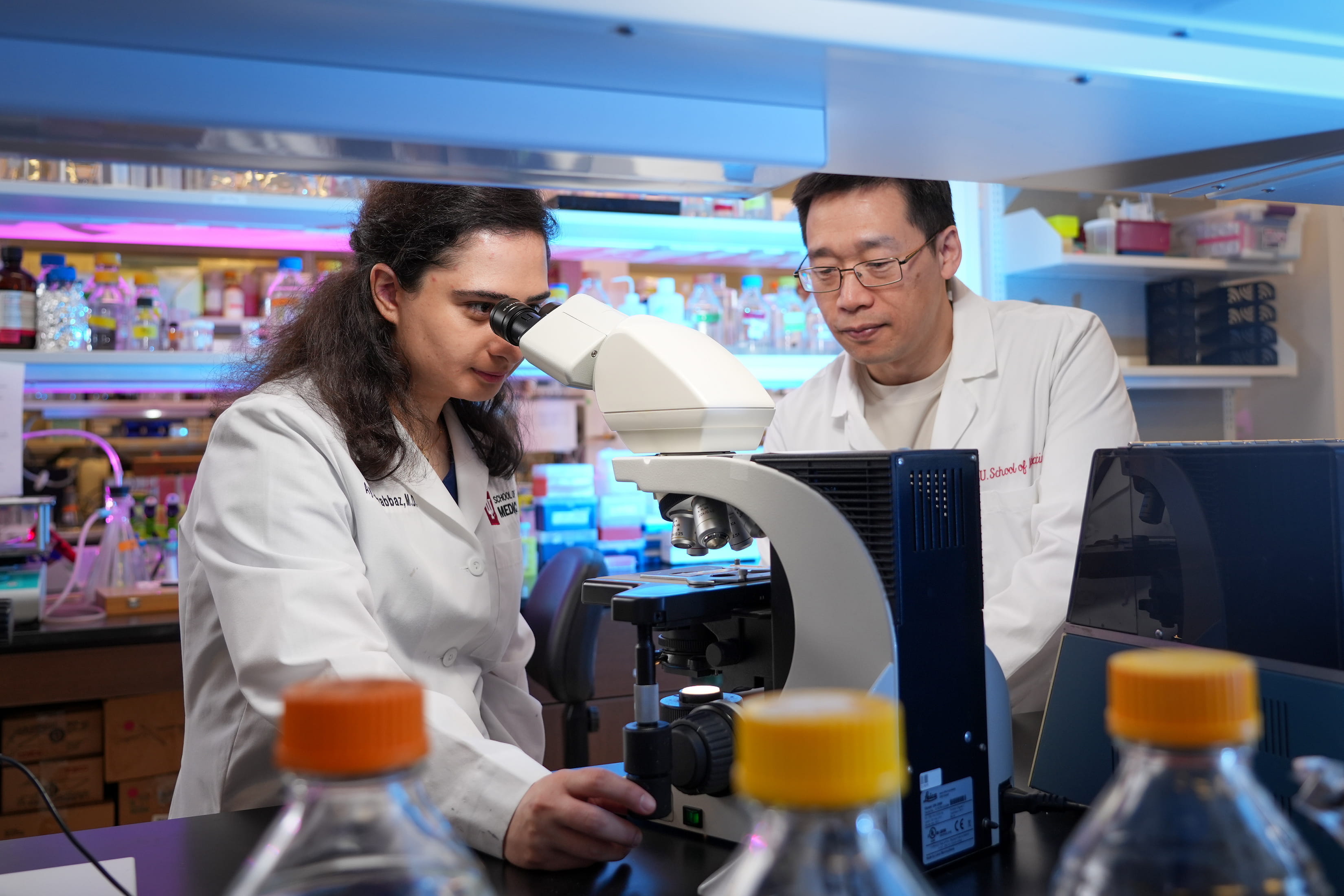 two researchers in white coats work in a lab