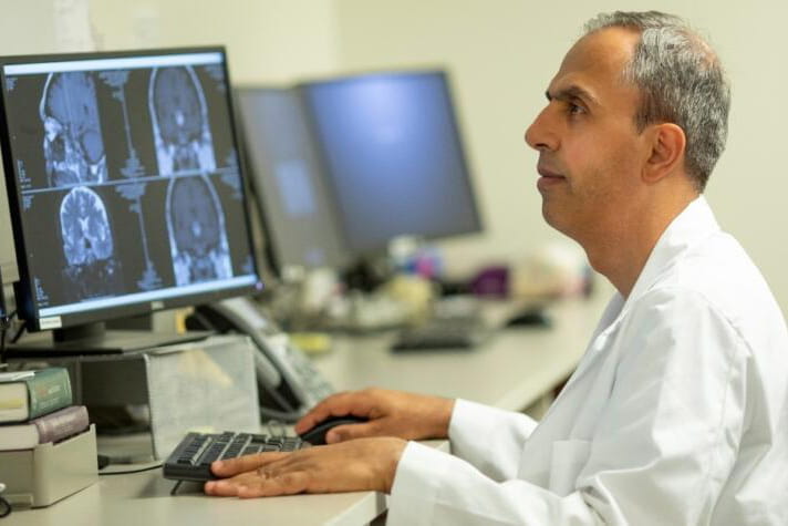 A male student analyzes brain images on a computer.