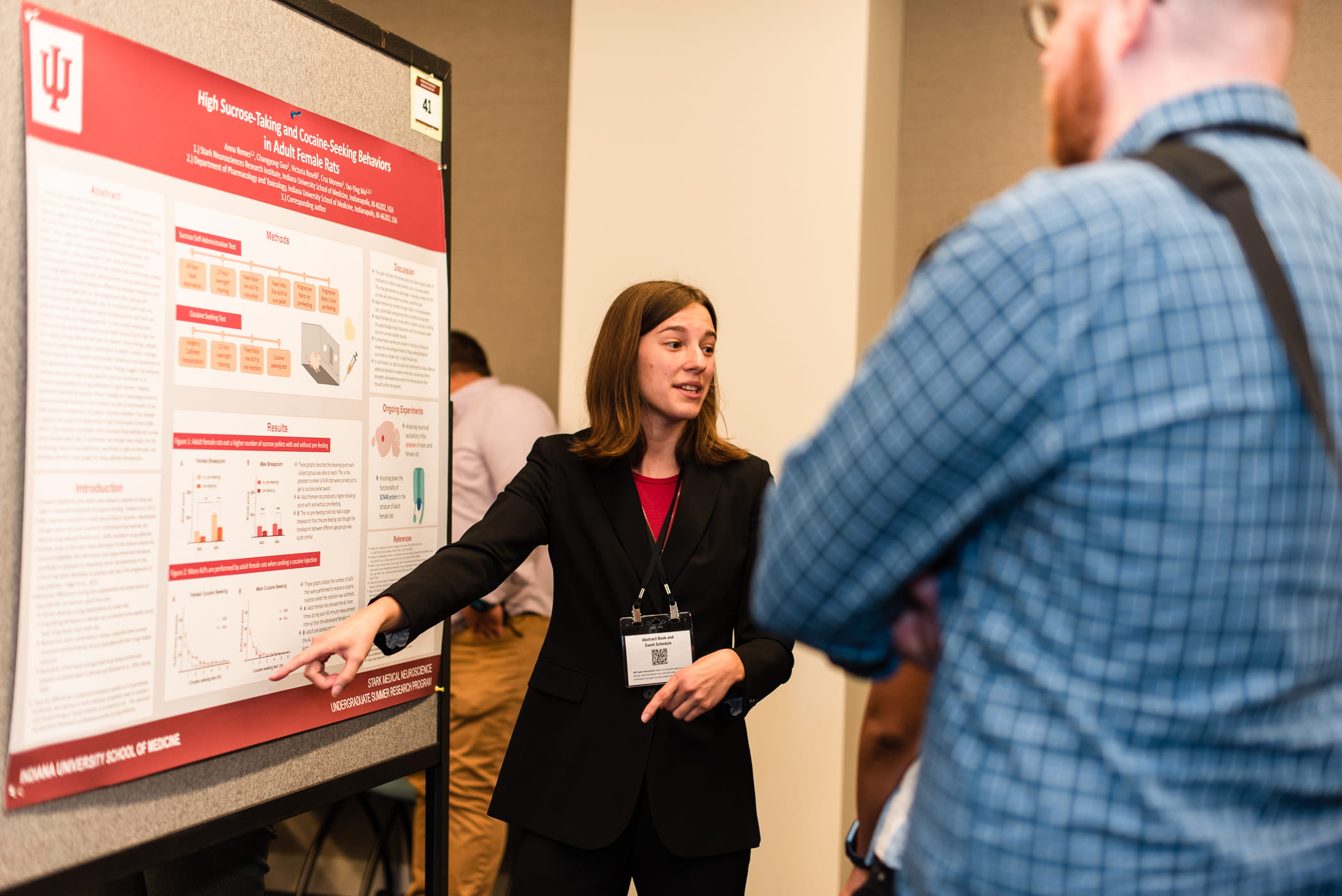Anna Remes presents her research poster to a person at a symposium
