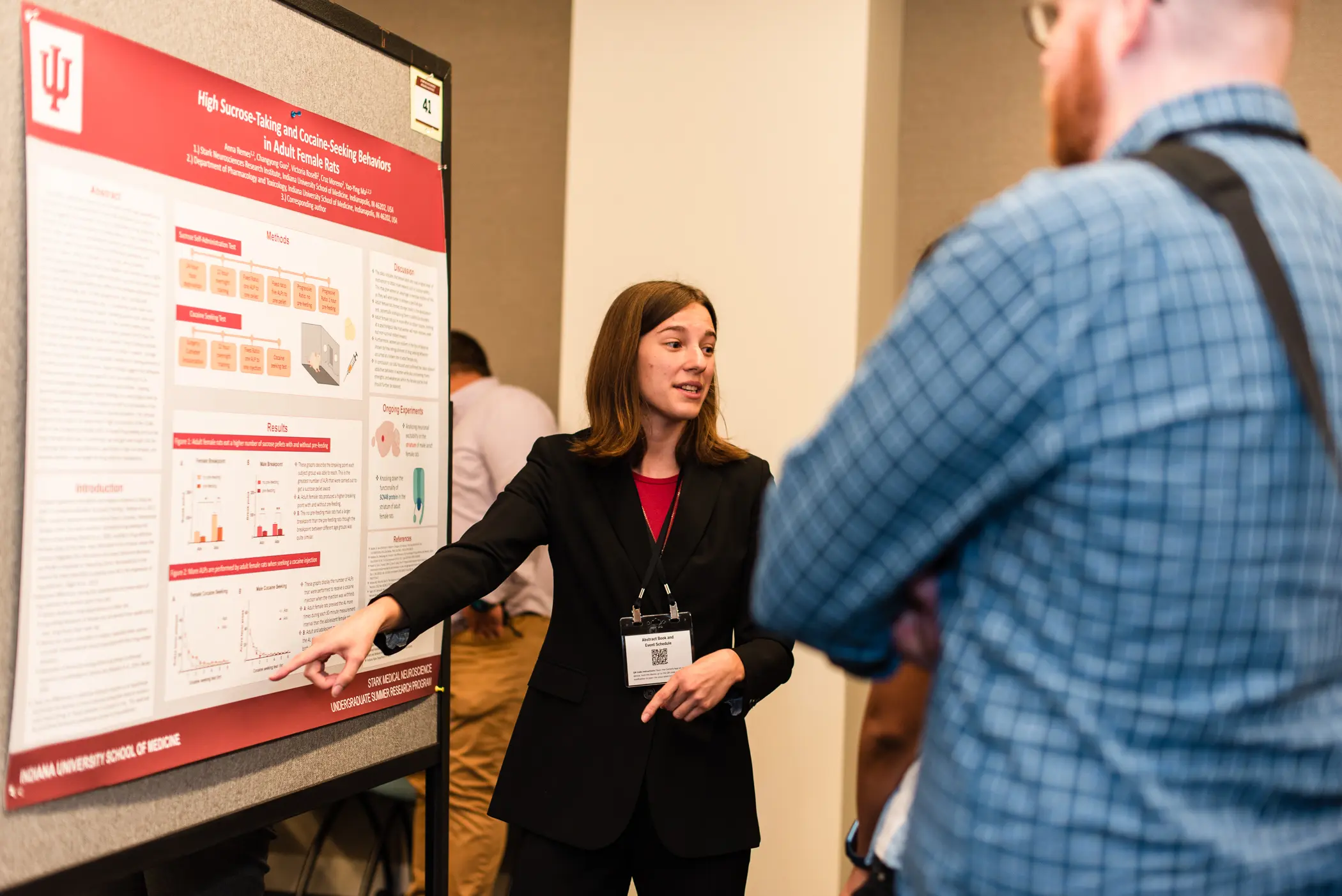 Anna Remes presents her research poster to a person at a symposium