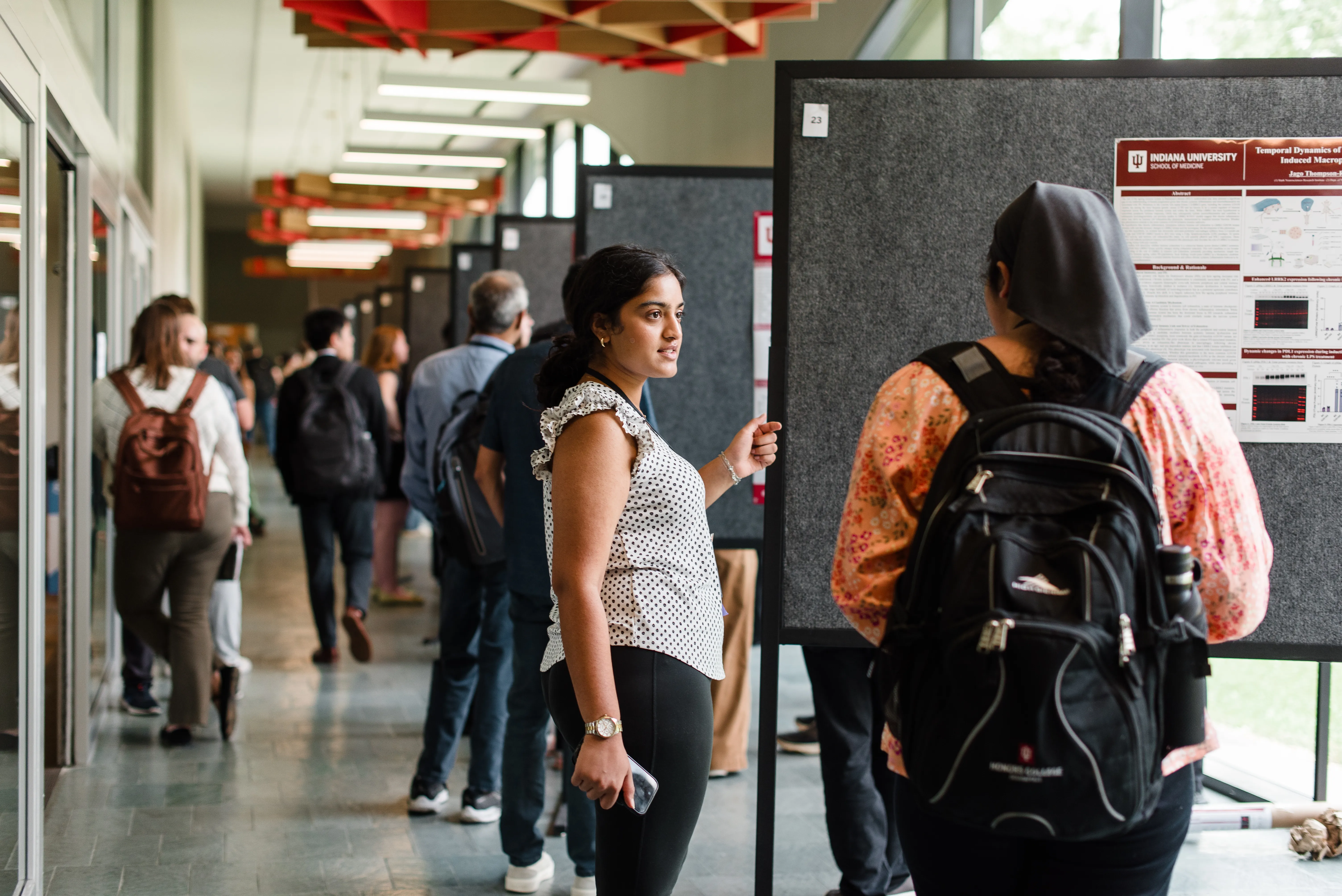 students stand near poster boards in a long room
