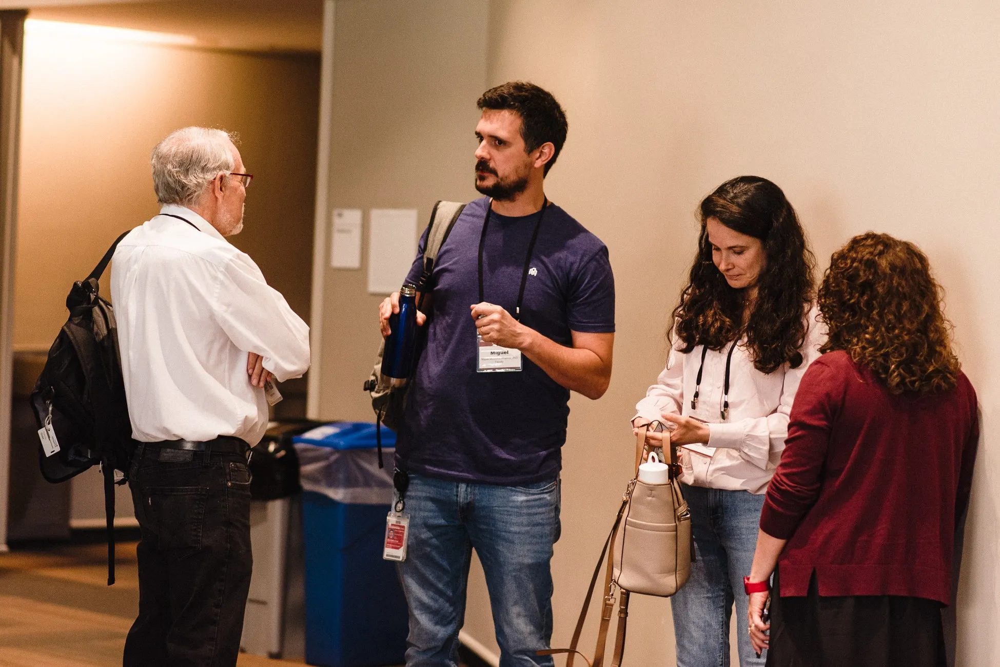 four people stand near one another at a symposium and two people talk