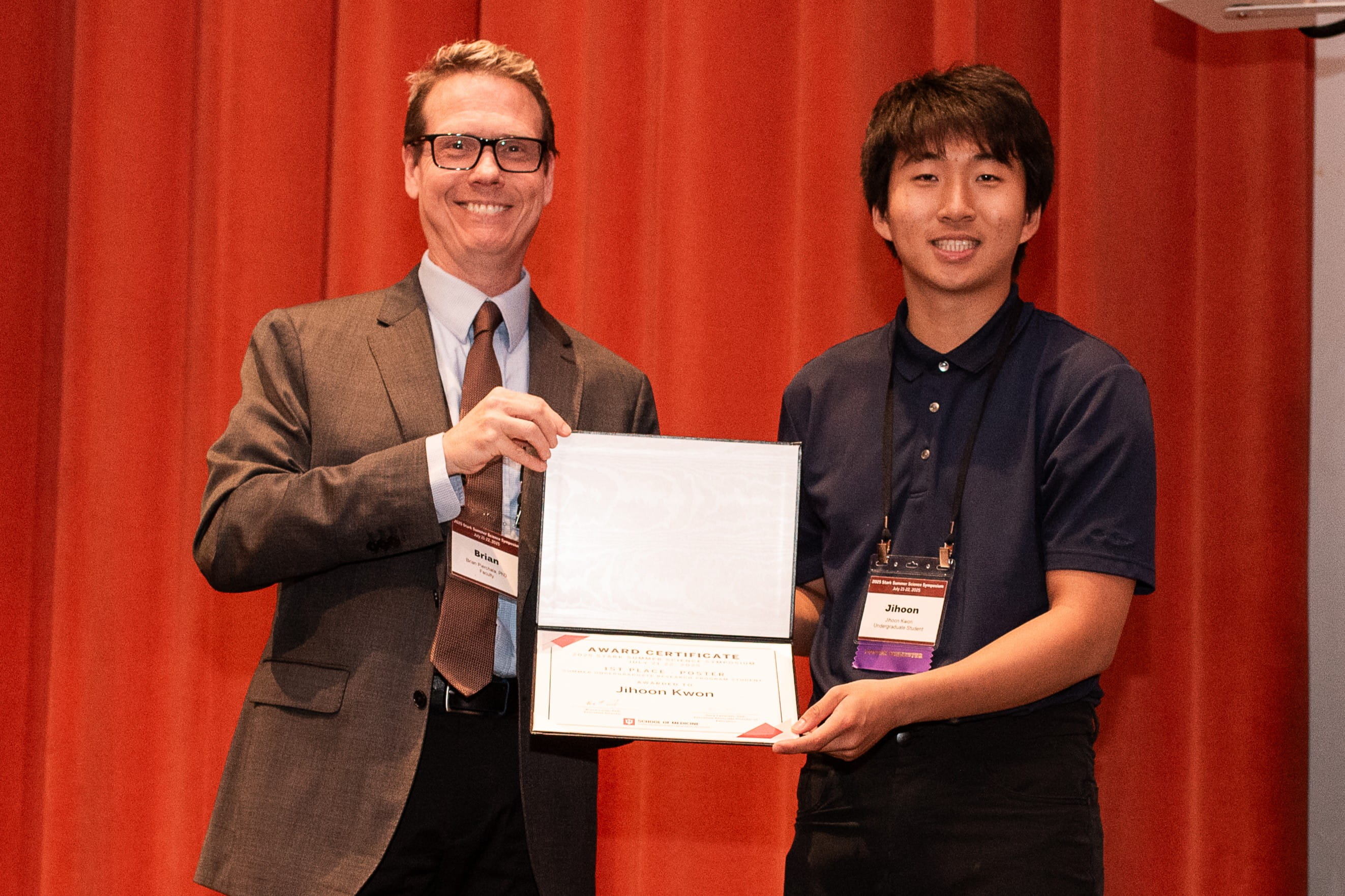 Jihoon Kwon holds an award certificate with Brian Pierchala
