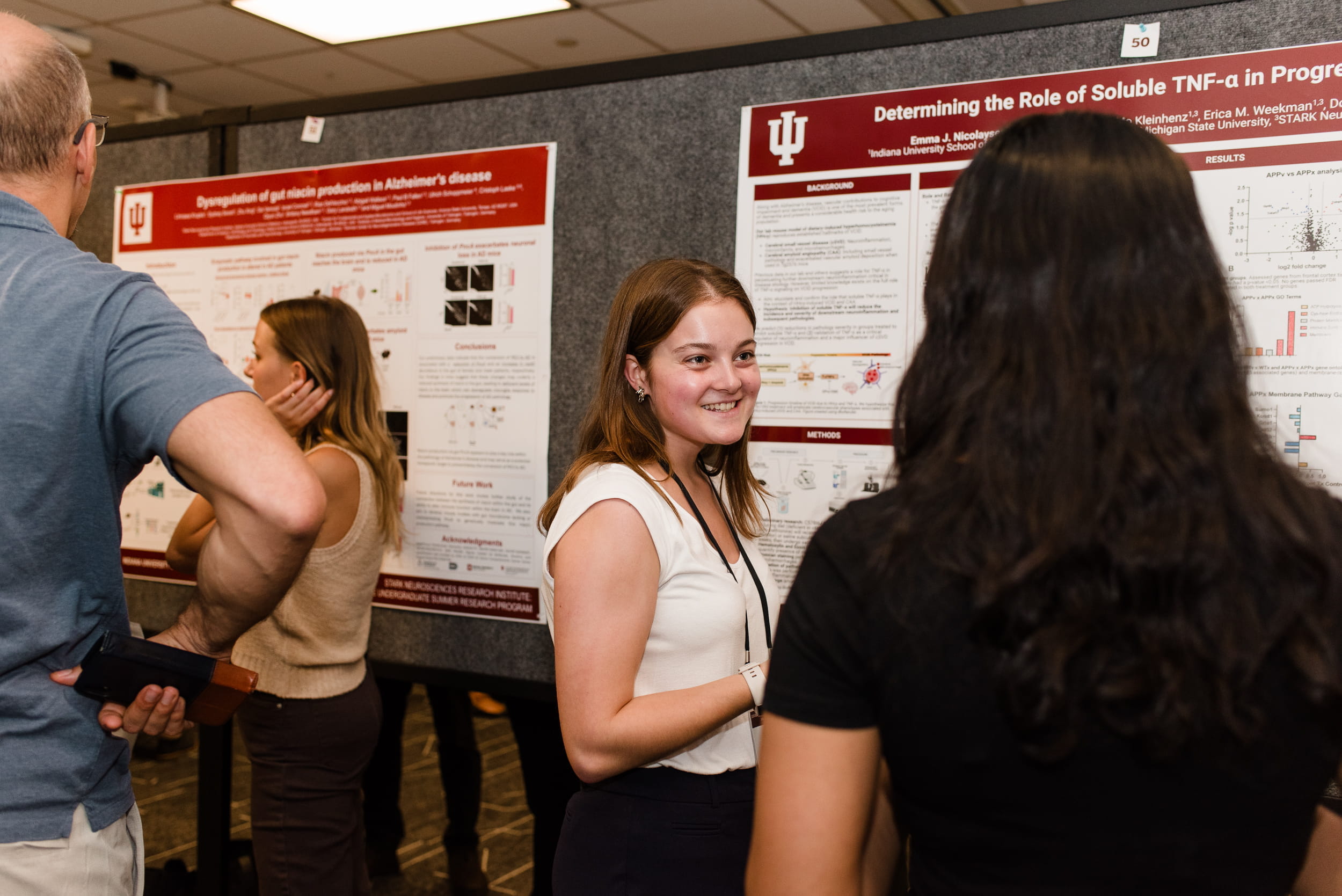 a student presents research on a poster to attendees at the symposium
