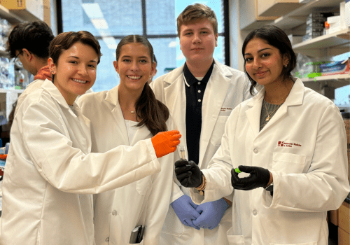 4 high school students posing in a lab