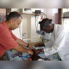 Chandy John, MD, and colleague examining a young malaria patient