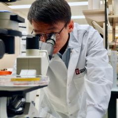 Ji Zhang, PhD, looking through a microscope