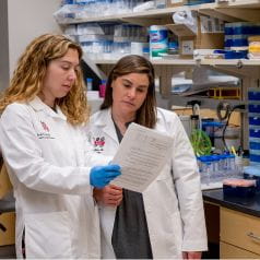 Emily Sims, MD, and Jamie Felton, MD looking at a document in a lab
