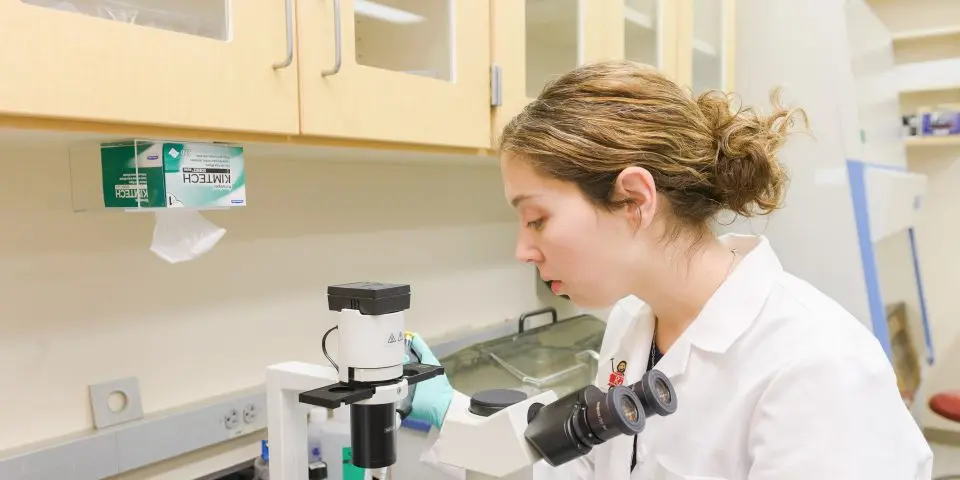 Emily Sims looking at a sample under a microscope