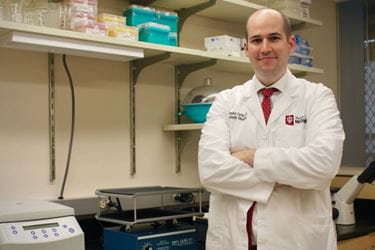 Chris Collier stands in his lab with his arms folded.